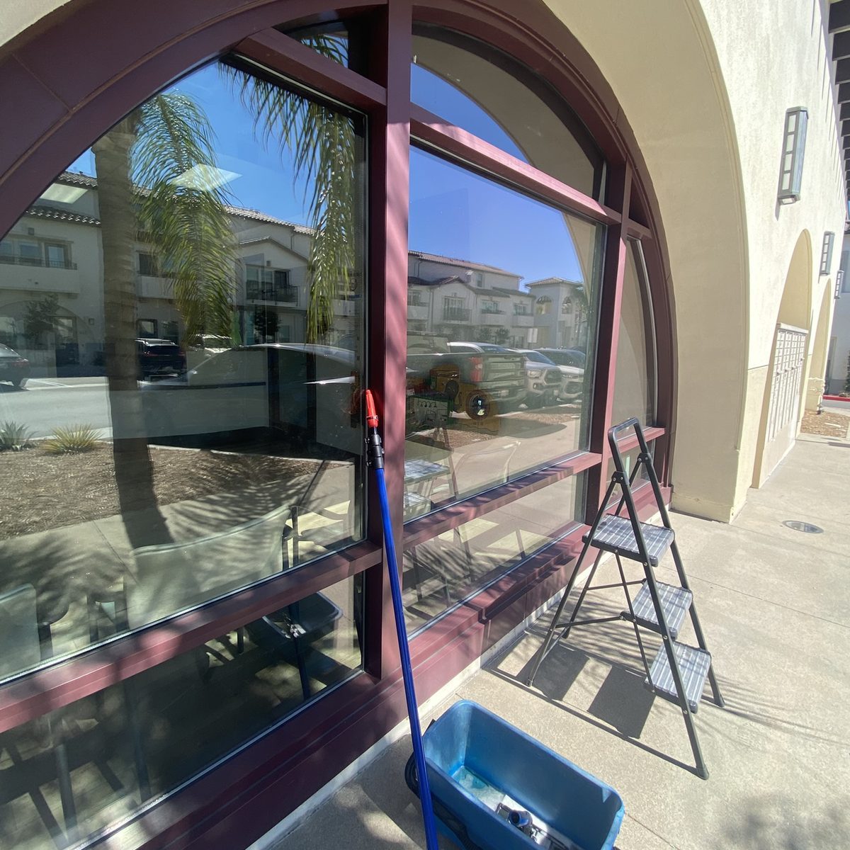 Campista cleaning the arched windows of a San Diego storefront