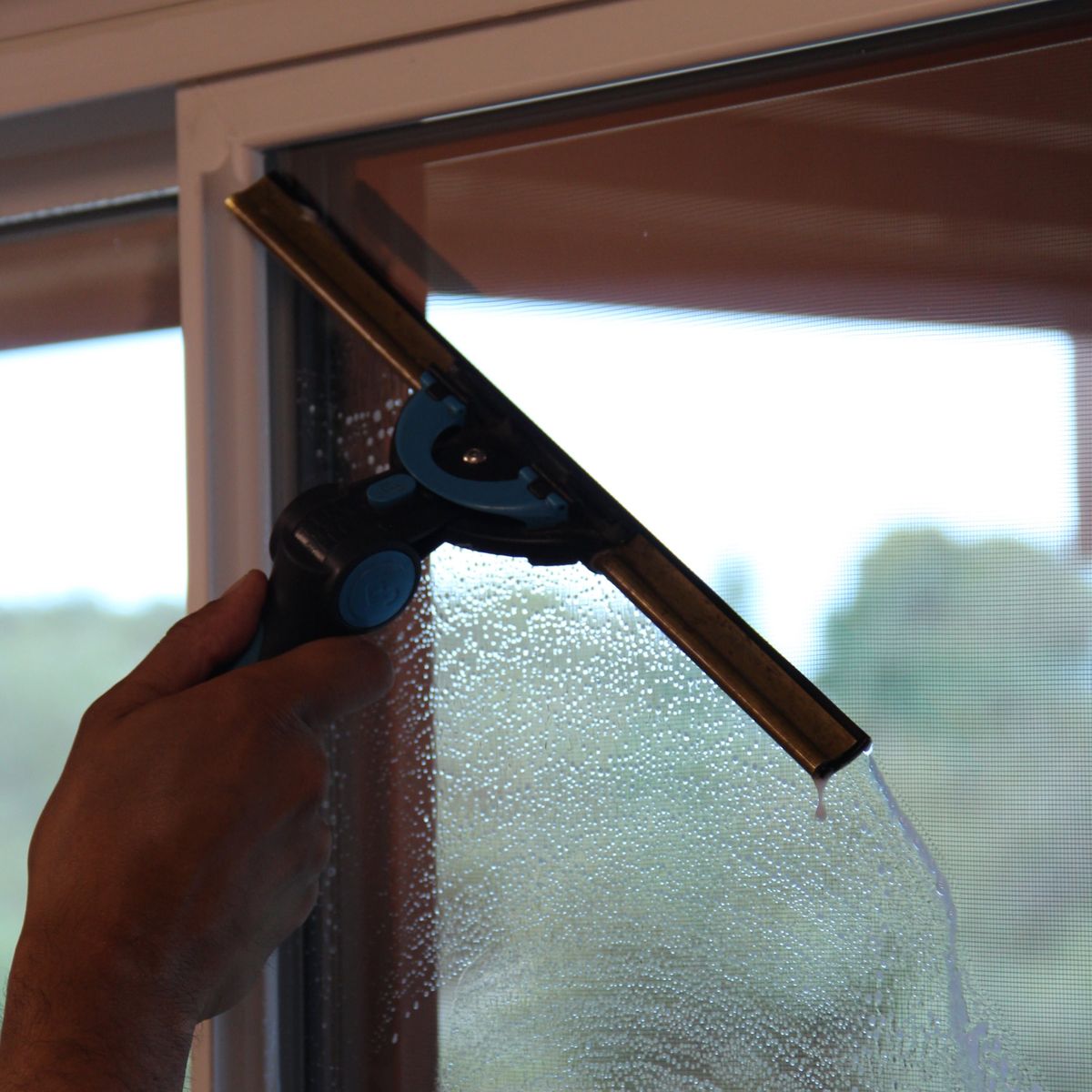 Squeegee clearing a wet window pane